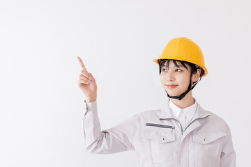 指差しをする作業服の女性
