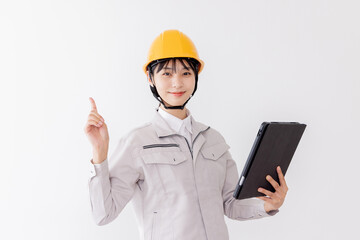 タブレットを使用しながら指差しをする作業服の女性
