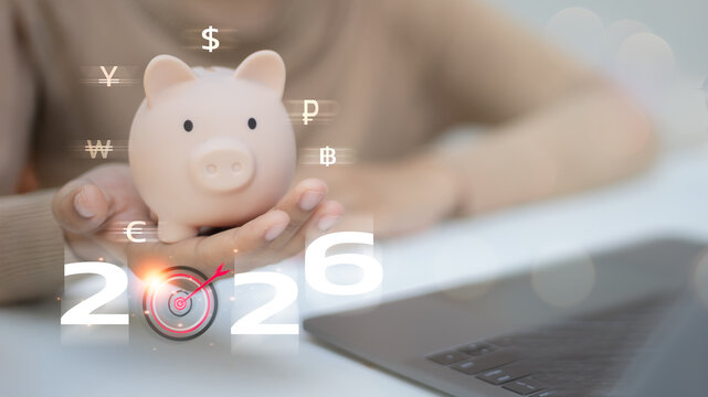 A person holding a piggy bank with multiple currency symbols and the year 2026, featuring a target icon.
