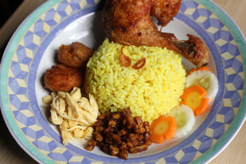a plate of yellow rice with fried chicken and vegetables