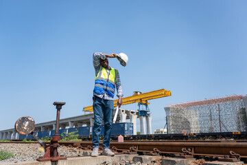 Construction Worker Shielding Eyes from Sun, Tired Construction Engineer Man Wiping Sweat Under the Hot Sun, African American Builder with Hard Hat and Plans