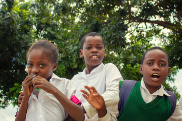 Real photo of cheerful African kids in school uniforms, enjoying time together outdoors. A natural moment full of smiles, youth, friendship, and positive energy. 