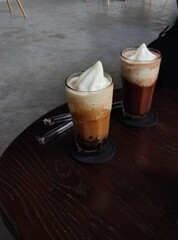 A glass of coffee latte with cream on the table at the cafe