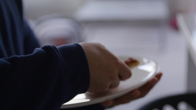 Hand putting large piece of pineapple pizza on plate and walking to table - close up