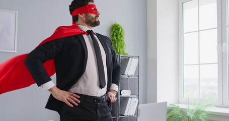 Business man in formal suit and superhero face mask and cloak working in office with laptop. Portrait of a funny confident attractive male company employee. 4k video. Slow motion video. - Powered by Adobe