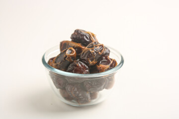 Dried dates in transparent bowl on white background