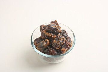 Dried dates in transparent bowl on white background