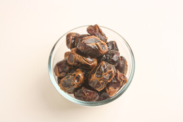 Dried dates in transparent bowl on white background