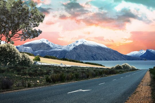 Fototapeta Two-lane asphalt road is leading toward sunset over lake and snow-capped mountains in flat design