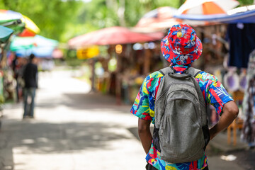 A cheerful tourist in a vibrant shirt walks through a Thai street market, enjoying the atmosphere and connecting with local culture