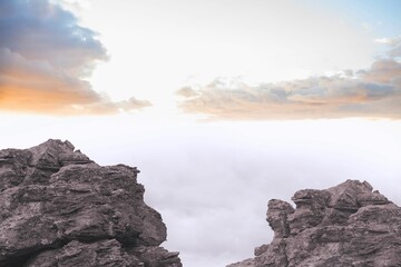 Obraz premium Pair of rugged rock formations are showing cloud-filled chasm at sunrise in flat design