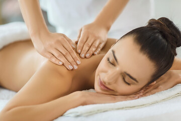 Fototapeta premium Masseuse performing back massage for pleased woman client during spa treatment, relax care, enhancing pleasure and body therapy in a peaceful salon environment of wellness and comfort.