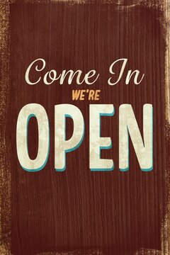 Fototapeta Displaying vintage style painted sign reading Come In We're OPEN on distressed wood panel