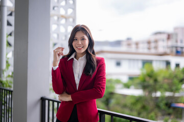Smiling asian businesswoman posing on balcony of modern office building