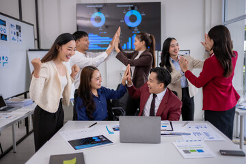 Enthusiastic business team celebrating successful project with high fives in office