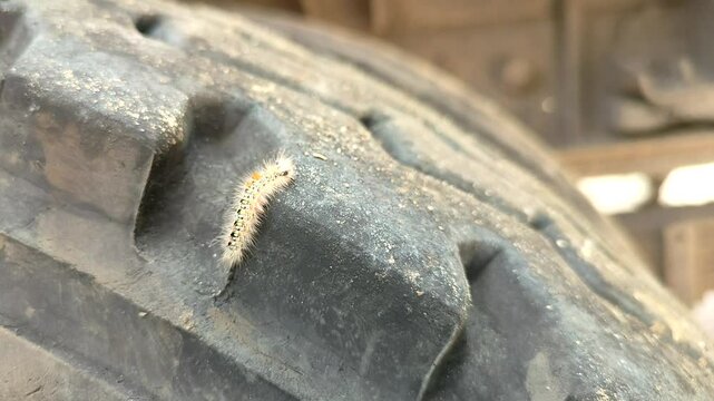Close-up of a worn, textured tire with a visible puncture or damage. Industrial or automotive concept