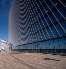 The wall of an office building is made of glass and concrete .