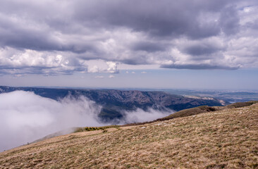 View from the mountain to the clouds below. Mountain landscape with clouds in the valley.