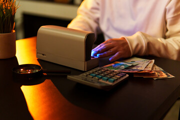 Cashier verifying colombian banknotes with currency detector machine