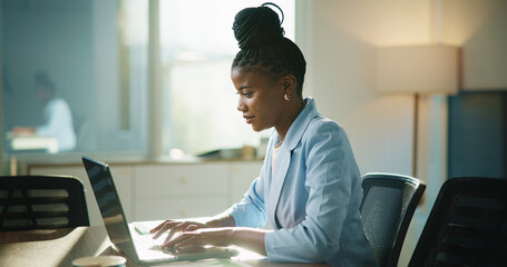 Business, laptop and black woman in office, typing and email for payroll schedule. African person, accountant and employee in workplace, pc or budget report with financial website or funding proposal