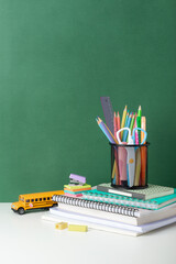 School supplies arranged with a green chalkboard background for education themes, back to school concept