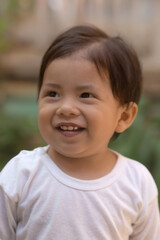 A young child with a white shirt and brown hair is smiling
