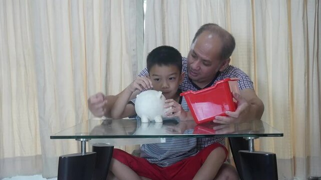 Father and son put coins into a piggy bank together.