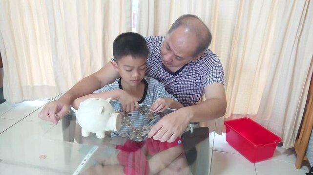 Father and son put coins into a piggy bank together.