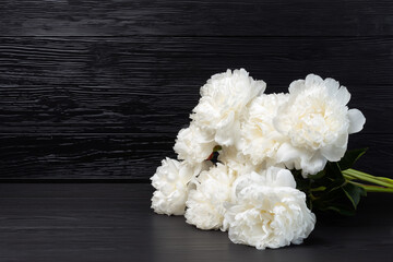 Bouquet of white peonies on black table background..