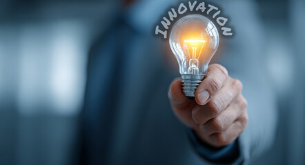 A businessman holds a glowing light bulb in his hand, symbolizing innovation, creativity, and visionary thinking—key elements driving business growth and success.