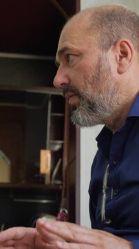 An engaged and artistic mood is captured as a bald man with a beard actively plays a djembe drum, looking up with an expressive and focused gaze. This shot is ideal for depicting musical performance