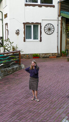 Blonde girl listening to message on mobile phone, holding it to her ear, standing, near original...