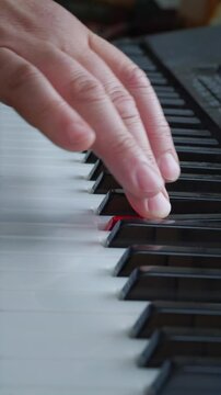 A creative and musical mood is captured by a close-up of a hand gracefully pressing the black and white keys of a piano or keyboard, highlighting the artistry of playing music