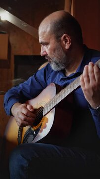 A creative and musical mood is captured by a close-up of hands expertly strumming the strings of an acoustic guitar, highlighting the intricate details of playing and the production of sound
