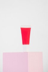 Red lipstick, small tube, and empty space on white background.