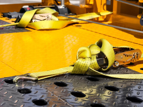 Heavy-duty yellow straps secured on a textured surface during construction work at a building site
