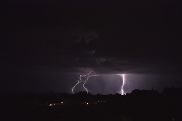 Lightning bolts striking the ground during a storm in Arizona. City lights are in the foreground.