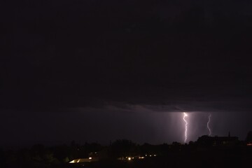 Lightning bolts striking the ground during a storm in Arizona. City lights are in the foreground.