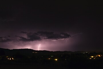 Lightning bolt striking the ground during a storm in Arizona. City lights are in the foreground.