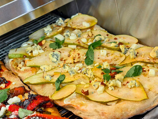 Delightful flatbread topped with sliced pear, blue cheese, and fresh herbs served in a cozy...