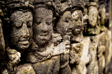A close-up of weathered stone carvings, possibly from Borobudur Temple, showcasing ancient Indonesian art and detail