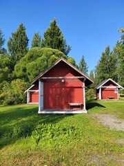 Red Wooden Cabins in Finnish Countryside Surrounded by Lush Green Trees