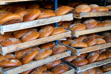 Freshly baked bread stacked on wooden shelves in a local bakery during the morning hours