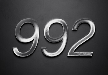 Chrome metal 3D number design of 992 on grey background.