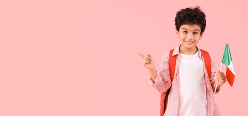 Little schoolboy with Mexican flag pointing at something on pink background with space for text