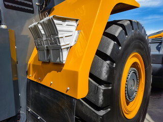 Heavy machinery tire and fender details capture in bright sunlight at construction site during daytime activity