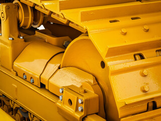 Heavy machinery components highlighted in bright yellow during construction at a job site in the afternoon sun