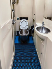 Clean restroom interior on a train featuring a toilet and sink with modern design in a compact space