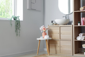 Interior of bathroom with sink bowl on wooden cabinet and shelving unit