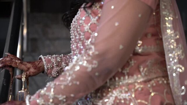 Pakistani Indian bridal showing wedding dress, pink flowers, bangles jewelry and mehndi design